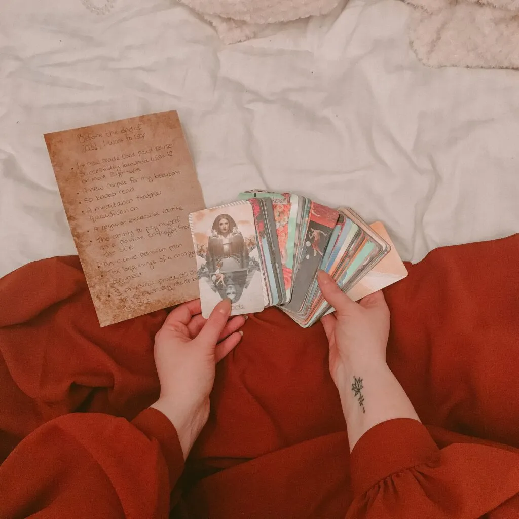 Hands holding a tarot deck over a notebook