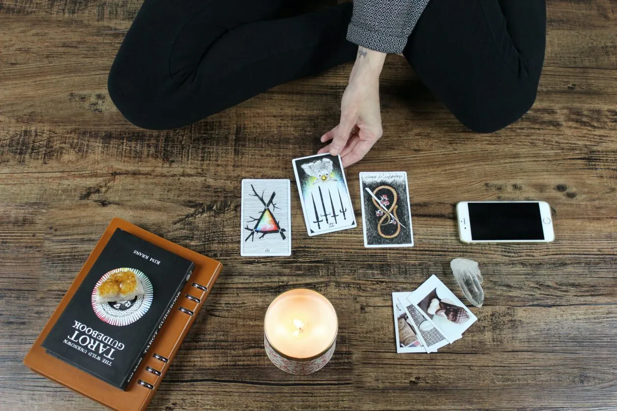 Three tarot cards being placed on a wooden table