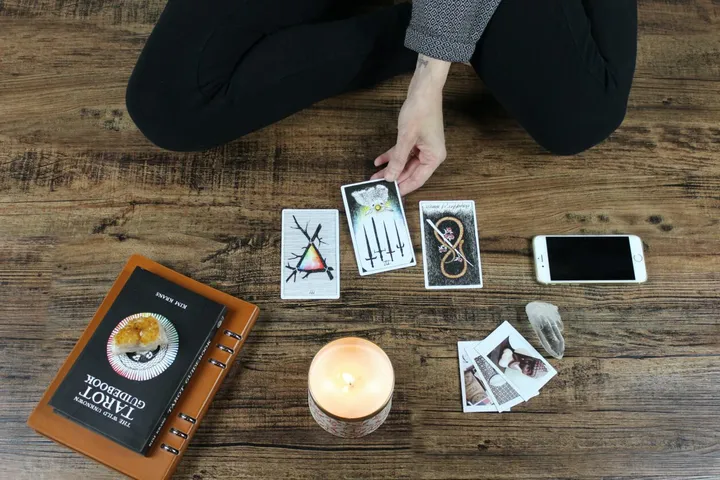 Three tarot cards being placed on a wooden table