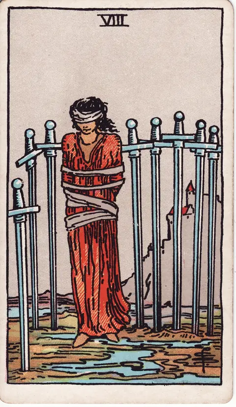 A blindfolded and bound woman stands among eight swords on wet ground, with a castle on a hill behind her.