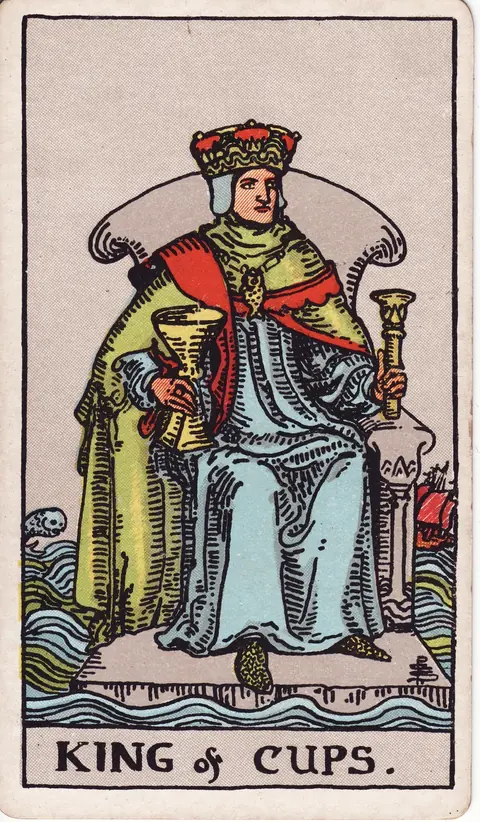 A crowned king sits on a gray stone throne amid a rough sea, holding a cup and scepter, with a fish pendant, a sailing ship and a leaping sea creature nearby.
