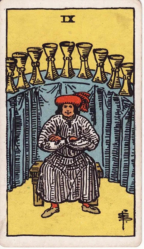 A satisfied man in a white robe and red hat sits with folded arms before nine golden cups arranged in an elevated semicircle.