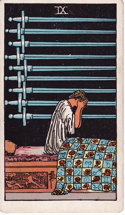A woman sits up in bed with her face in her hands beneath nine swords, her quilt patterned with roses and astrological symbols.