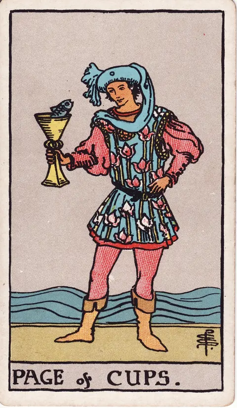 A young page in a floral blue tunic and flowing blue headwear stands by the sea, looking at a fish emerging from a golden cup.