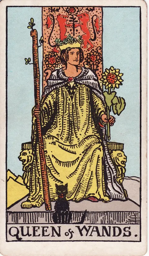 A queen holding a sunflower and wand on a lion-decorated throne with a black cat at her feet