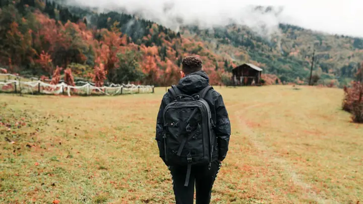 A hiker walks through an autumn landscape.