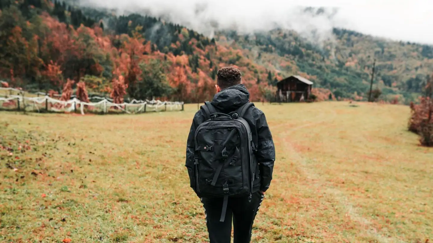 A hiker walks through an autumn landscape.