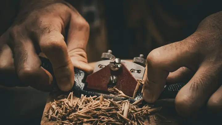 A craftsperson uses a hand plane to shape wood.
