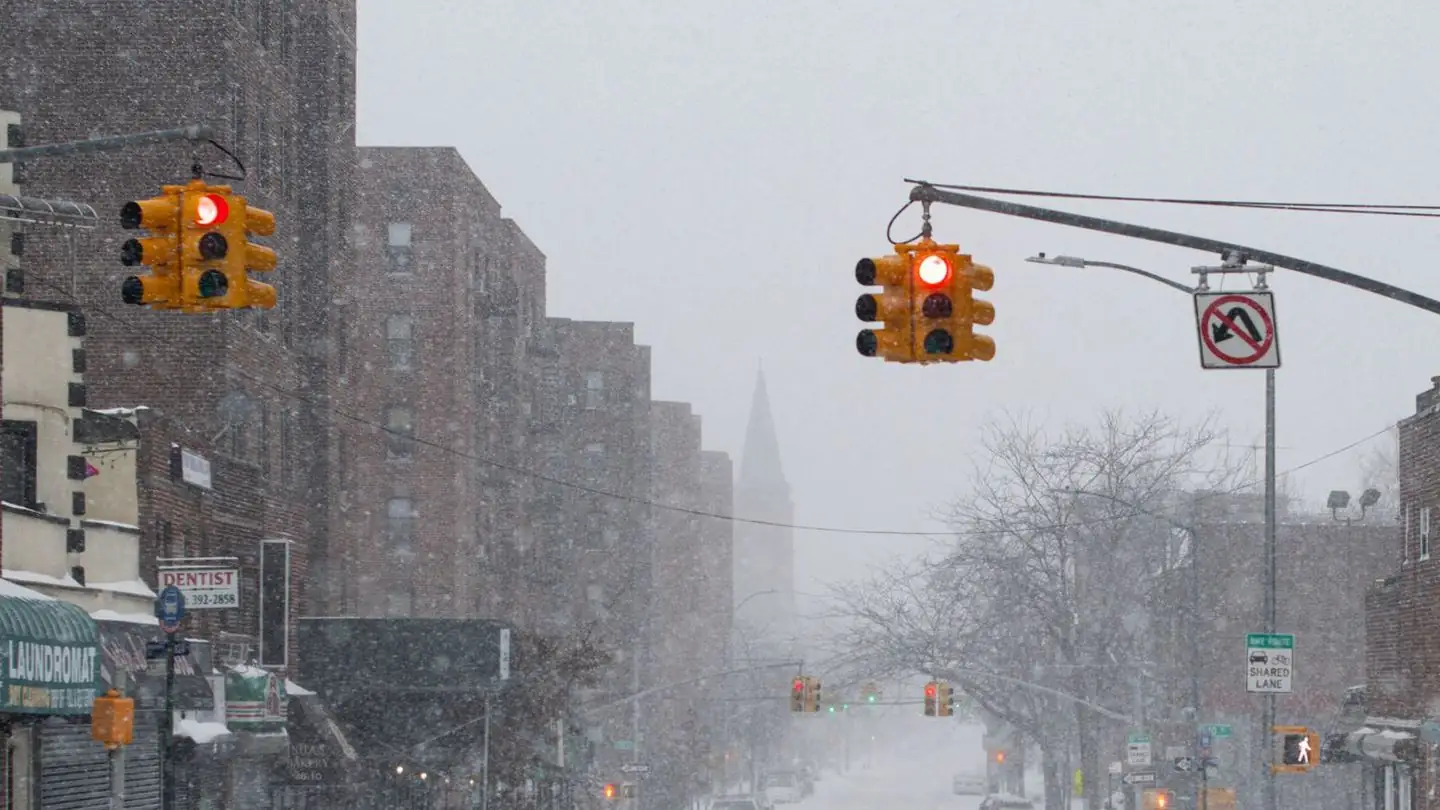 A lone pedestrian walks along a snow covered city street.