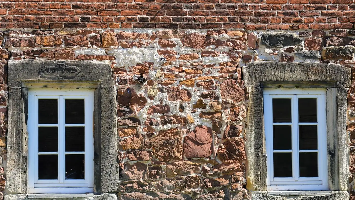 Two white framed windows in an old stone building.