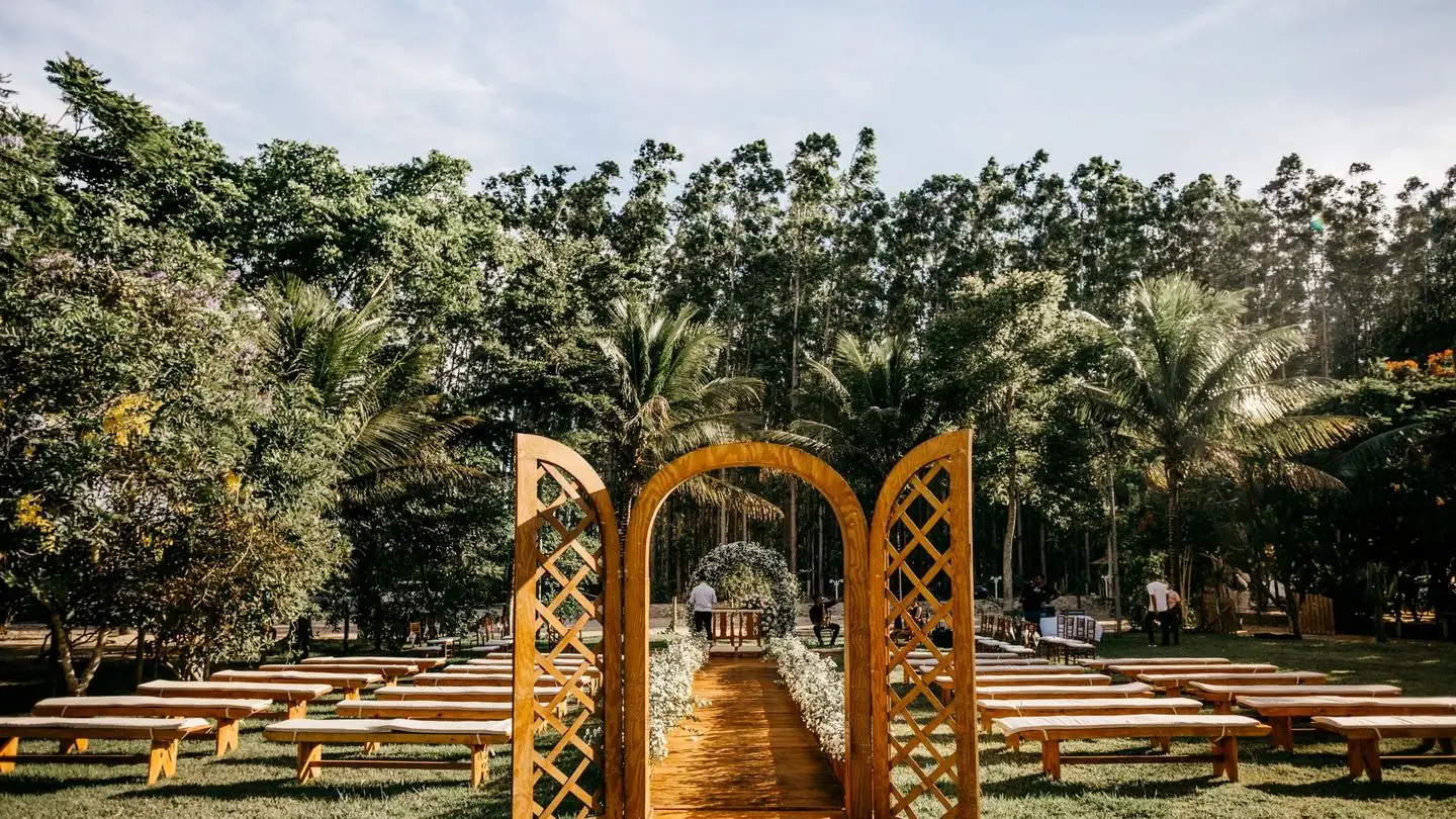 A wedding arbor and guest benches stand in a green park.
