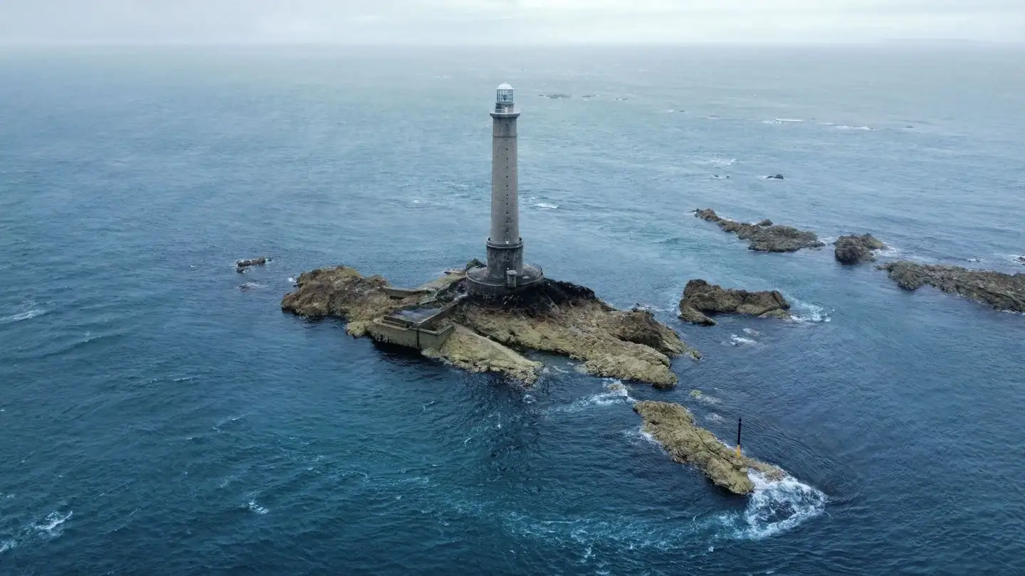 A lighthouse stands on a rocky island surrounded by the sea.