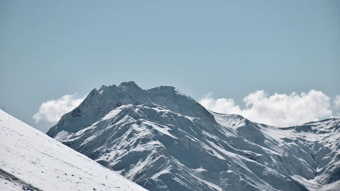 Snow covers mountain peaks beneath a clear blue sky.