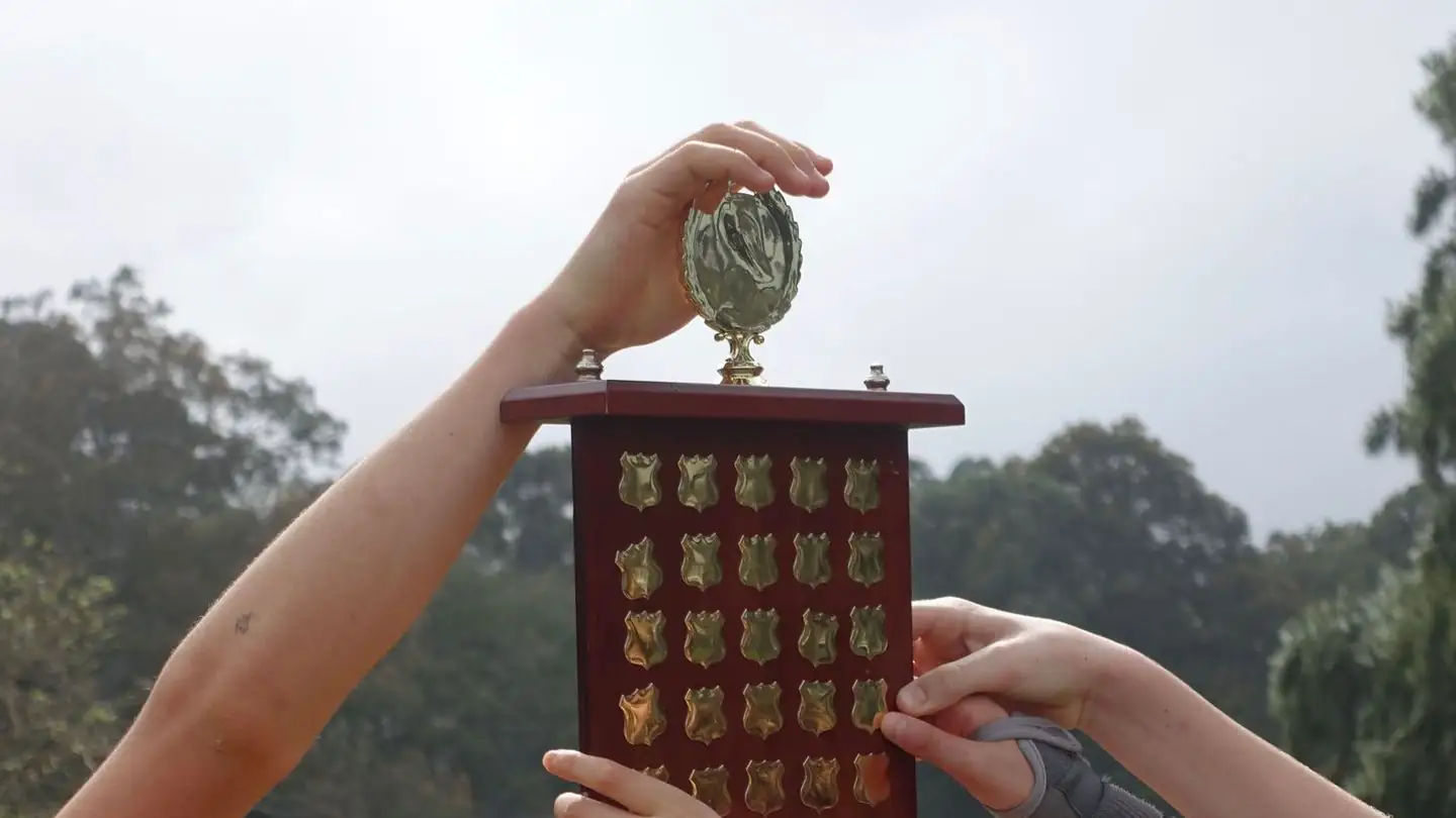Young athletes raise a wooden trophy together.