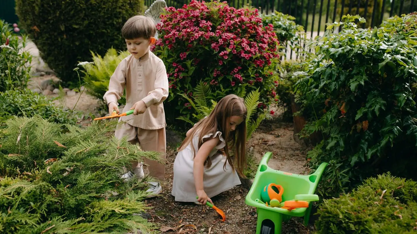 Two children garden together with tools.