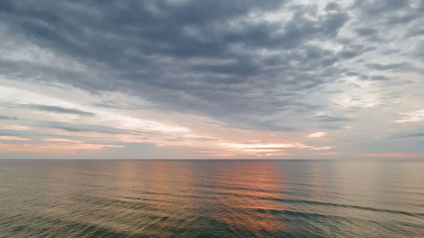 Sunset light breaks through clouds over the sea.