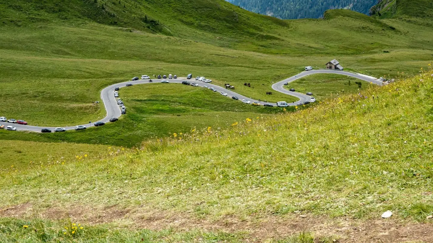 A winding road crossing green hills beneath distant mountains