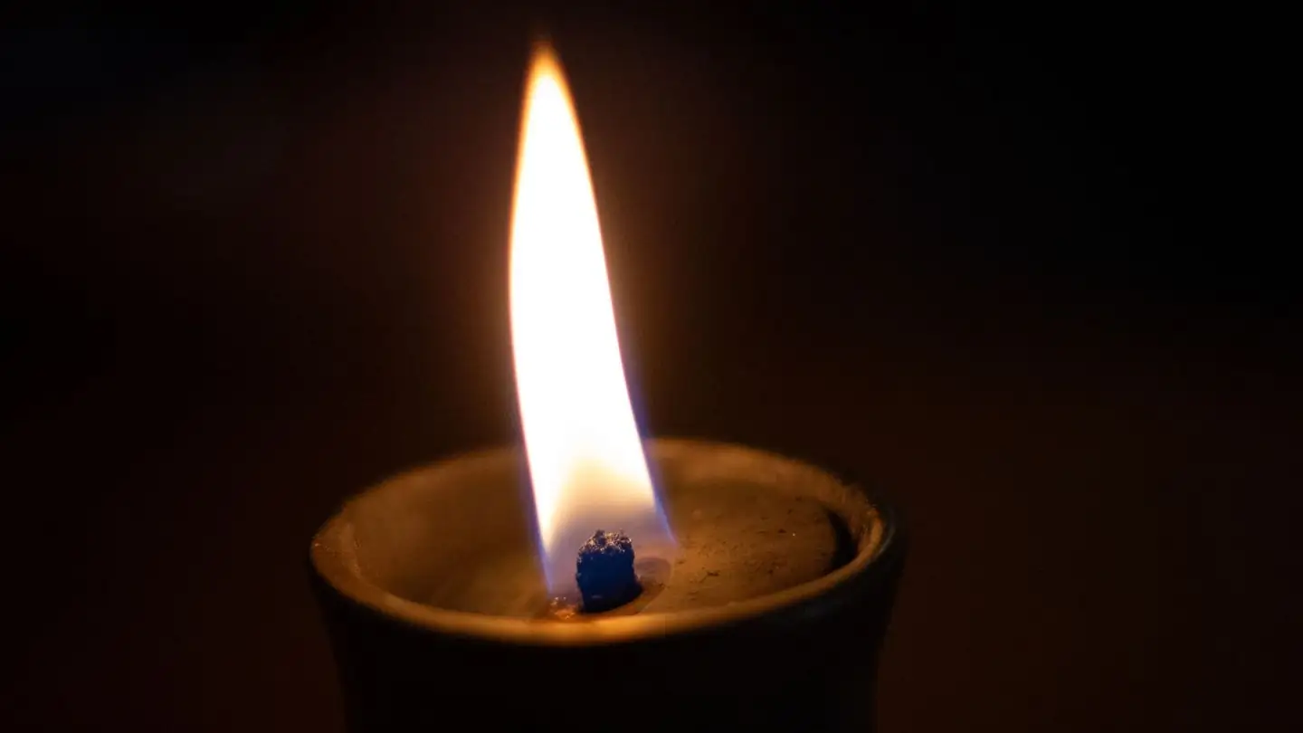A candle flame glowing against a dark background
