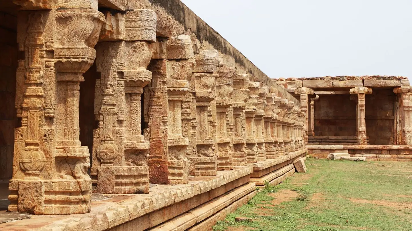 A row of carved stone pillars around an open temple courtyard