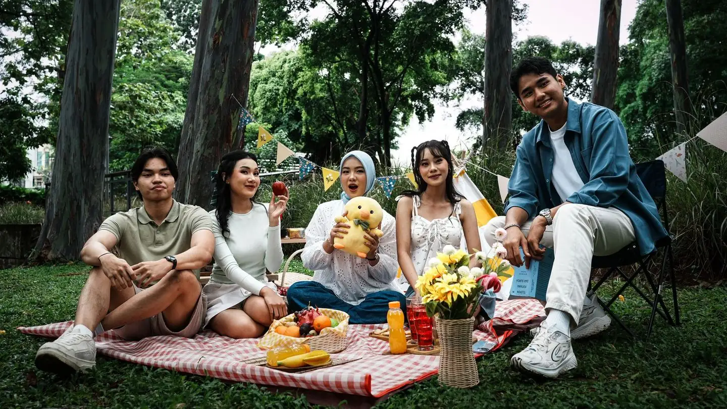 Friends share a picnic in a green park.